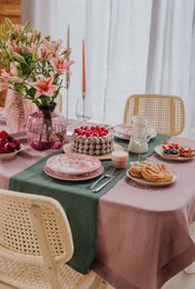  Forest green linen table runner, available in 40x150 cm, 40x200 cm, and 38x100 cm sizes. Features a rustic, natural style with a floral centerpiece and assorted desserts on the table.