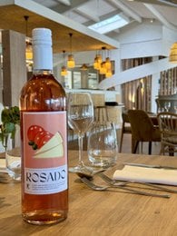 Rosé wine bottle with glass, wooden table, and restaurant interior. Vibrant, fruity rosé wine with glass and restaurant setting.