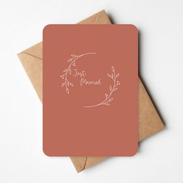 A simple yet elegant greeting card with a delicate floral design and the text "Just Married" in a cursive font. The card is made of a warm, terracotta-colored material and comes with a matching envelope.