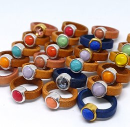 Colorful leather rings with various gemstones and shapes, including round, oval, and heart-shaped stones in a variety of colors such as green, pink, blue, and orange.