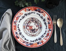 Decorative ceramic dinner plate with a floral and geometric pattern in shades of red, blue, and white.