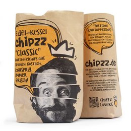 Classic potato chips in a paper bag with a man's face on the packaging. The chips are described as "Edel-Kesse Chipzz Classic".