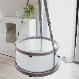 A white, round crib with a gray frame and hanging mobile. The crib appears to be a 3-in-1 design that can be used as a crib, bassinet, and playpen.