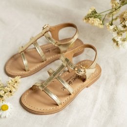Gold strappy sandals with floral accents, suitable for young girls. Features a simple, minimalist design with adjustable straps for a comfortable fit.