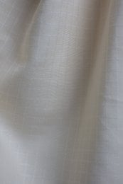 Off-white linen fabric with subtle tile pattern texture, lightweight natural material for dresses and garments.