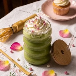 Green matcha latte powder set with whisk, bowl, wooden accessories, pink gift box packaging, ceremonial tea kit.