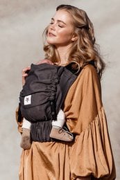 Grey baby carrier with adjustable straps and pockets for storage.