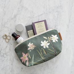 A green cosmetic bag with a floral print featuring white and pink flowers. The bag is made of organic materials and is suitable for storing makeup and other personal items.