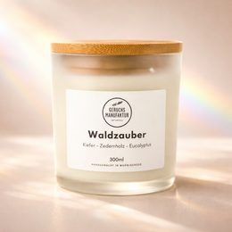 A round, tall candle with a wooden lid, featuring a forest-inspired scent of Waldzsauber (forest magic).