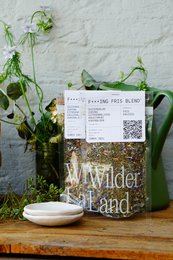 Ceramic tray with "Wilder Land Tea F**king Fresh" text, featuring a rustic, natural design with green plants and blue flowers.
