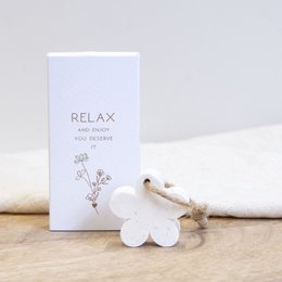  A small, white gift box with the text "RELAX and enjoy you deserve it" on the packaging. Inside the box is a white ceramic flower-shaped soap.