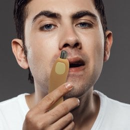 Nose hair trimmer, gold color, for grooming and personal care.