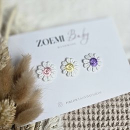 Cheerful mix of hair clips for kids, featuring a heart-shaped clip in a peach color and a floral clip in a neutral tone.