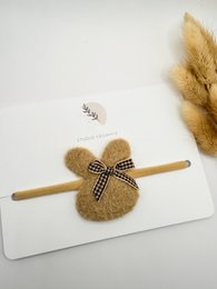  Soft, plush hairband with a bow accent in a neutral color palette, perfect for accessorizing kids' outfits.