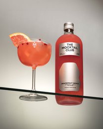  A 99cl bottle of Mocktail Grapefruit Grace, a non-alcoholic grapefruit-flavored beverage, served in a glass with a grapefruit slice.