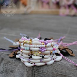  Handmade shell bracelets in various colors and designs, including shells with flowers, beads, and threads. Ideal for kids' fashion accessories.