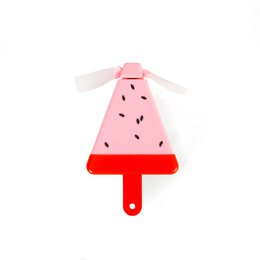 A pink and red watermelon-shaped mini fan with a white propeller. The fan has a playful, whimsical design and appears to be made of plastic.