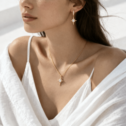  Gold-toned necklace with a pendant in the shape of a star, featuring a pearl-like accent.