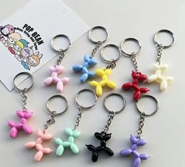 Colorful balloon dog keychains in pink, yellow, red, white, purple, blue, and black with metal rings.