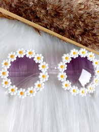 White and pink daisy-framed sunglasses for kids, featuring a round shape and a playful, floral design.
