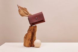 Burgundy leather wallet with gold leaf accent, compact and minimalist design, suitable for everyday use.