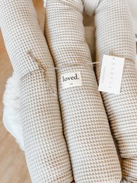  Soft, textured, off-white decorative pillow with "loved" text detail.