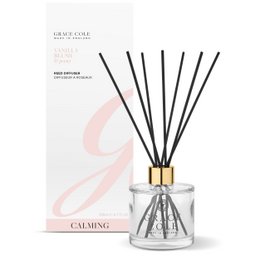  A tall, cylindrical glass diffuser bottle filled with a clear liquid and containing black reed sticks. The bottle has a gold-colored cap and is surrounded by a white and pink label that reads "Vanilla Blush & Peony Diffuser 200ml".