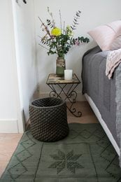 Olive green woven cotton rug with geometric pattern, medium size, suitable for use as an area rug.