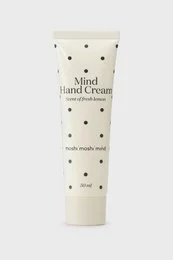 Cream-colored hand cream tube with black polka dot pattern, minimalist design, skincare product packaging.
