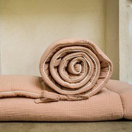  Nude-colored, rolled playmat with a soft, textured surface and a tied bow detail.