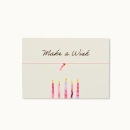 A birthday card with the text "Make a Wish" and an illustration of colorful birthday candles. The card is designed with a minimalist, handwritten style.