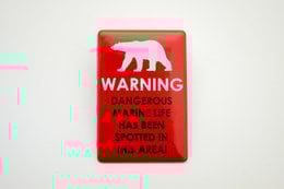 Rectangular enamel sign with warning about dangerous marine life in Svalbard area. Available in red, navy blue, and white color variants.