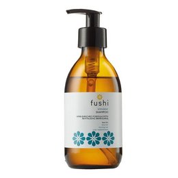 Herbal shampoo with amber-colored liquid in a glass bottle with a black pump dispenser. The label features a floral design and the brand name "Fushi".