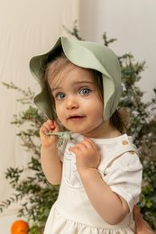 A soft, green bonnet with a bow detail, perfect for keeping a baby warm and cozy. Suitable for ages 0-12 months.