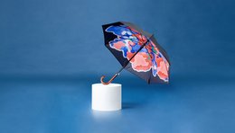 A straight art umbrella with a vibrant, abstract floral pattern in shades of pink, blue, and white against a black background.