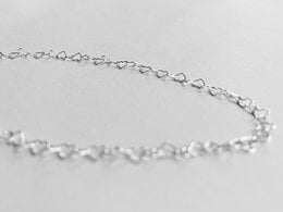 A delicate silver chain necklace with a connected heart-shaped design. The necklace features a simple, elegant style that can be worn for various occasions.