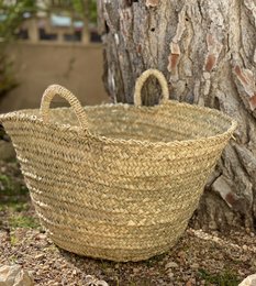 Large woven palm basket with handles, suitable for storage or decor.
