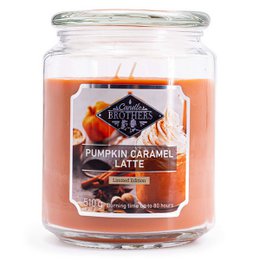 A large, round, glass jar candle with a pumpkin caramel latte scent. The candle has an orange-colored wax and a white label with the product name.