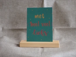 Greeting card with a green background and orange text that says "Met heel veel liefs", which translates to "With lots of love" in English. The card appears to be a good luck card.