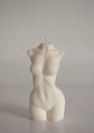 Tall, white, abstract candle in the shape of a female torso. Made of wax with a simple, minimalist design.