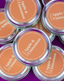 Medium-sized, round, orange-colored soy candles with apple and cinnamon scent.