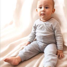 A grey and white striped organic cotton baby kimono bodysuit with long sleeves. Designed for newborns and infants up to 24 months old.
