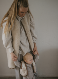 Long, beige merino wool body warmer with a high collar and loose, oversized fit. Suitable for men's casual or outdoor wear.