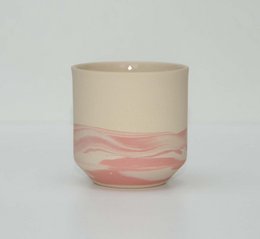 A pink and white ceramic mug with a wavy pattern.