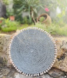 Round woven placemat in gray color with decorative shell-like border, suitable for use as a decorative tray or table accessory.