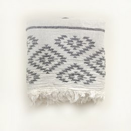 Gray and white patterned beach towel with tasseled edges and "Hello Turco" text and mustache graphic.
