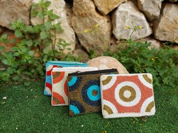  Colorful, patterned wallets made of woven fabric with circular designs in shades of blue, red, and tan.