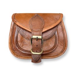  Genuine goat leather shoulder bag in a cross-body style, featuring a flap closure with a buckle detail, a single adjustable strap, and a classic brown color.