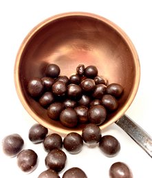 Dark chocolate-coated hazelnuts in a wooden bowl. Rich, indulgent chocolate flavor with crunchy hazelnut texture.