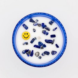 Blue candle with a smiley face design, containing various blue stones and a yellow smiley face symbol.